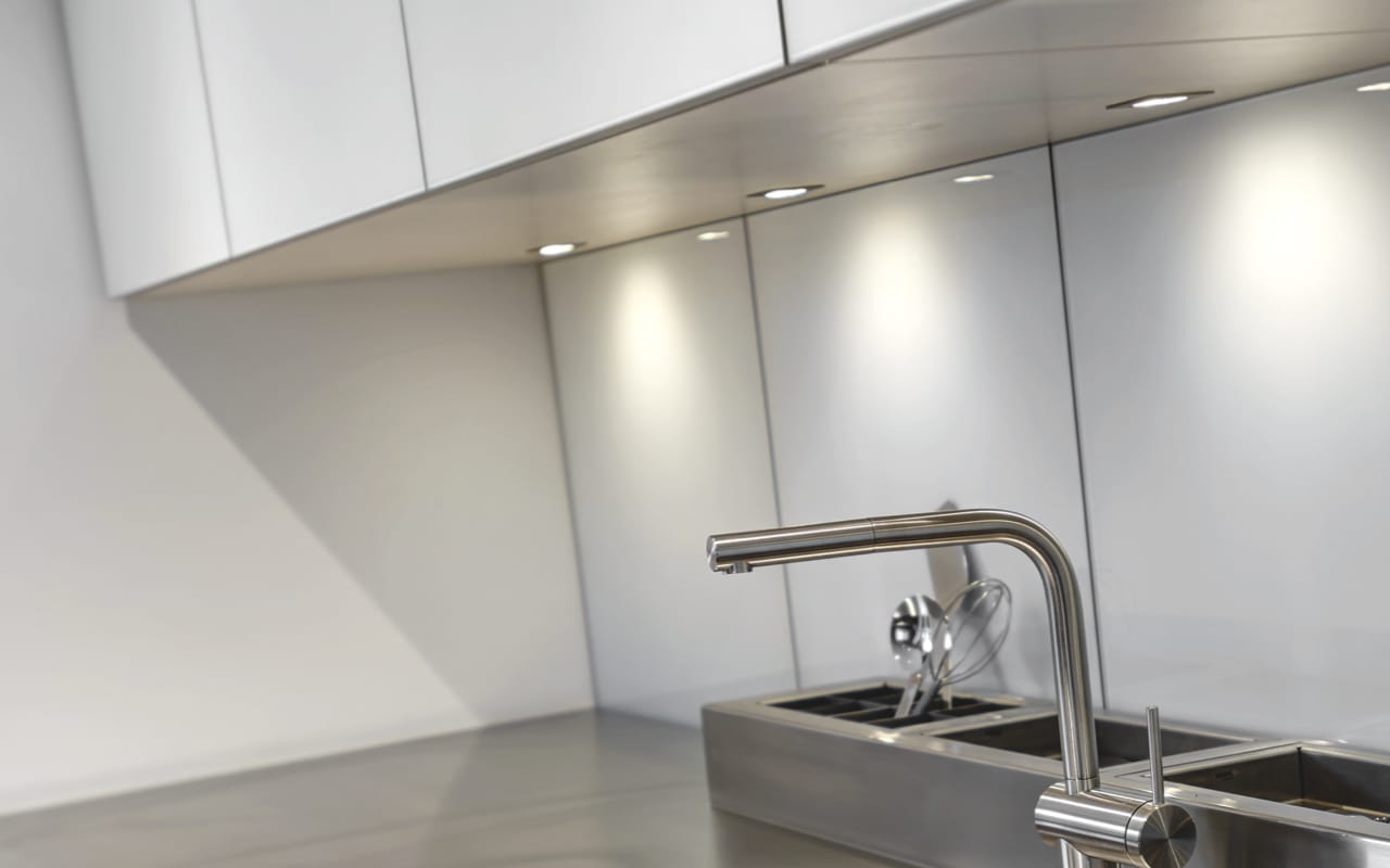 White Contemporary kitchen with grey countertops, grey utensil holder and minimalist silver faucet.
