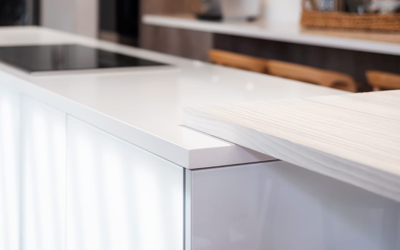 Close up of a white kitchen island with white countertops.